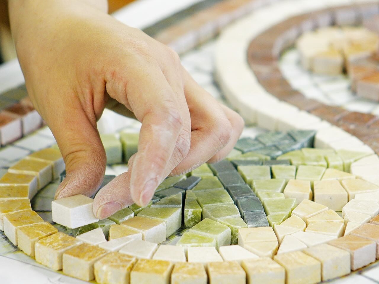 Hands placing mosaic tesserae